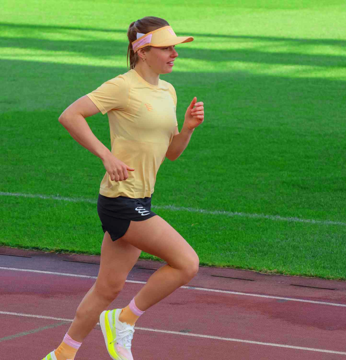 Femme athlète en pleine course sur piste, illustrant la physiothérapie du sport